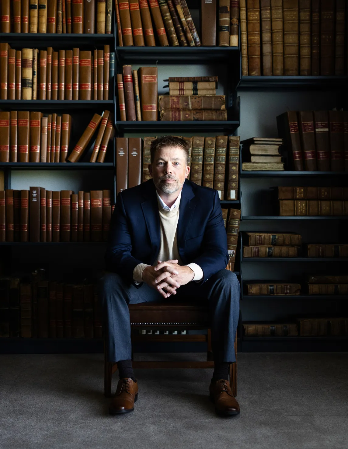 Don Seitz, broker and founder, seated among antique law books